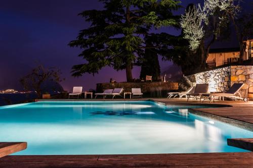 a swimming pool at night with lounge chairs around it at Bellevue San Lorenzo (Adults Only) in Malcesine