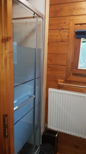 a glass refrigerator next to a wooden wall at Chalet Domaine du Hulobiet in Fromelennes