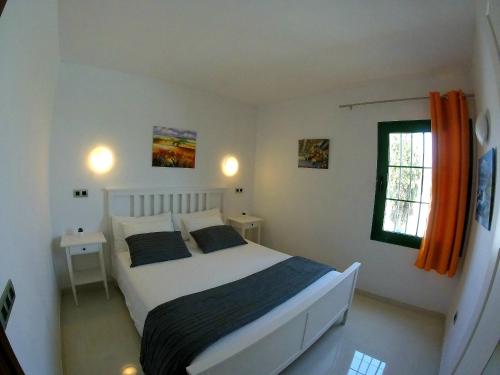 1 dormitorio con 1 cama y una ventana con cortinas de color naranja en Magmamia en Puerto del Carmen