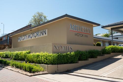 ein Gebäude mit Schildern an der Seite in der Unterkunft Noah's Mid City Motor Inn Muswellbrook in Muswellbrook