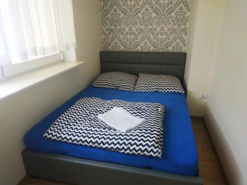a small bedroom with a blue bed and a window at Oskar Apartament Centrum PKP in Mińsk Mazowiecki