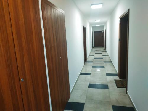 a corridor of a room with wooden doors and a tile floor at Oskar Apartament Centrum PKP in Mińsk Mazowiecki