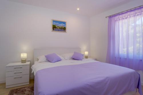 a white bedroom with a large white bed and a window at Apartmani Beatrice in Mali Lošinj