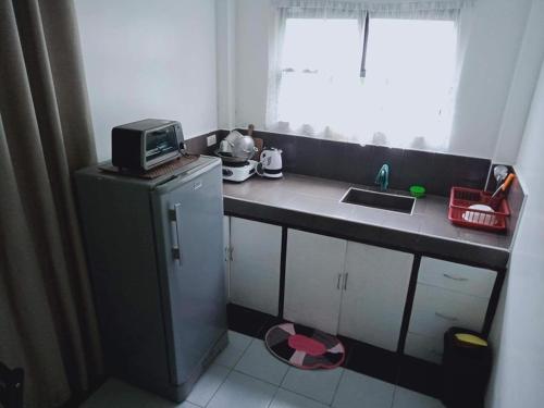 a small kitchen with a sink and a microwave at De Hagan Transient Baguio City in Baguio