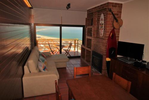 a living room with a couch and a television and a balcony at NAZARÉ SURF APARTMENT in Nazaré