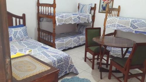 a room with a bed and a table and chairs at Pousada Nascimentos in Bertioga