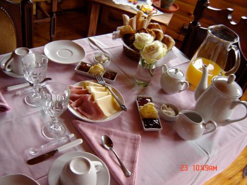 a table with a pink table cloth with food on it at Casa Puelo Hostería y Cabañas in Lago Puelo