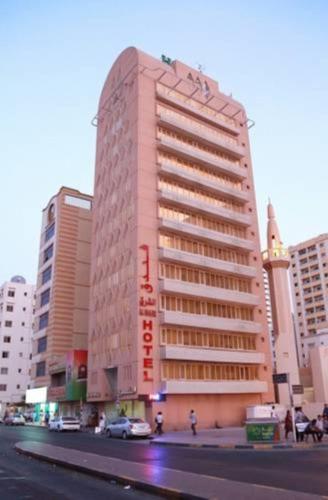 a tall pink building on a city street with buildings at Al Sharq Hotel in Sharjah
