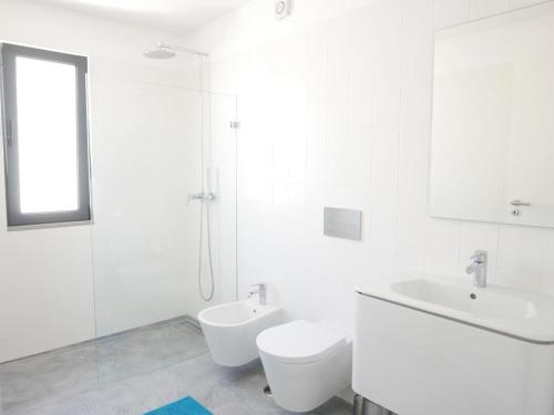 een witte badkamer met een toilet en een wastafel bij Casa na Carrapateira, Aljezur in Carrapateira