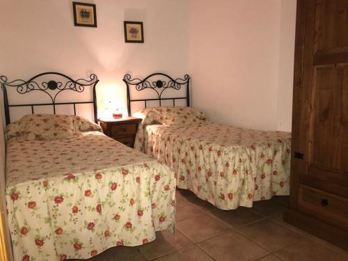 Un dormitorio con dos camas y una mesa con lámpara. en Casa Elvira, en Arroyo Frío