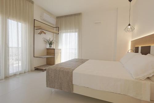 a white bedroom with a large bed and windows at Hedoné Design Experience B&B in Agrigento