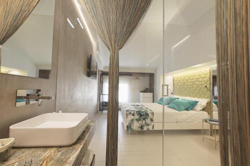 a bathroom with a sink and a bed and a tub at Hedoné Design Experience B&B in Agrigento
