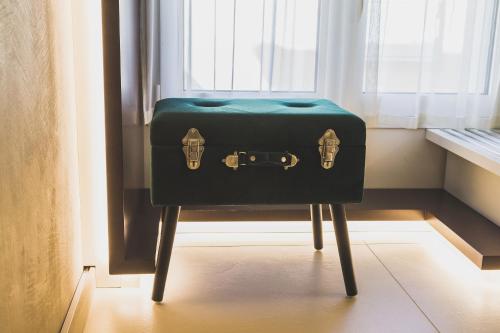 a green suitcase sitting on a stool in front of a window at Hedoné Design Experience B&B in Agrigento
