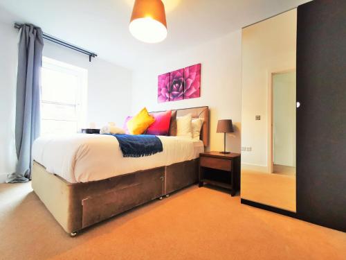une chambre avec un grand lit avec des oreillers colorés dans l'établissement Lovely Holiday Home in Birmingham City Center 3 Bedrooms House By HF Group, à Birmingham