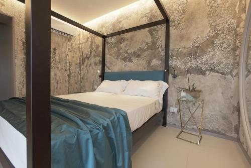 a bedroom with a bed and a concrete wall at Hedoné Design Experience B&B in Agrigento