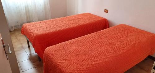 two beds with orange sheets in a room at Casa Guastuglia in Gubbio