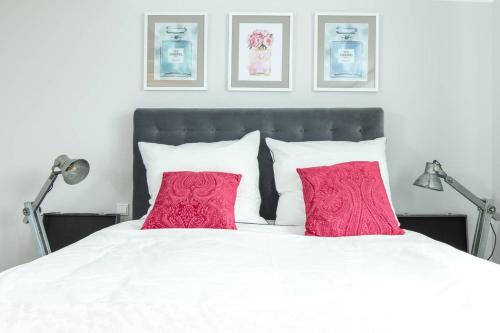 ein Schlafzimmer mit einem weißen Bett mit zwei roten Kissen in der Unterkunft PARIS · CHILLINGHOUSE # 5, 3 Min. vom ICE, NETFLIX, Garten in Siegburg
