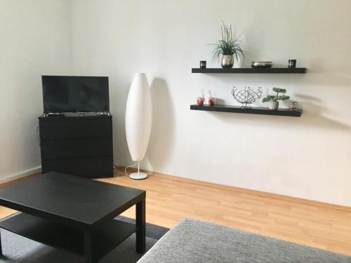 ein Wohnzimmer mit einem schwarzen Tisch und einem TV in der Unterkunft Apartment Living Leipzig in Großzössen