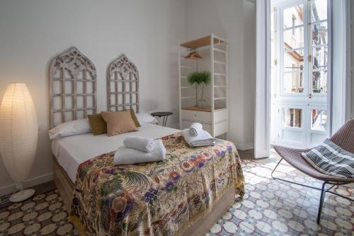 sypialnia z łóżkiem, krzesłem i oknami w obiekcie Apartamentos Las Musas de Cadiz w Kadyksie