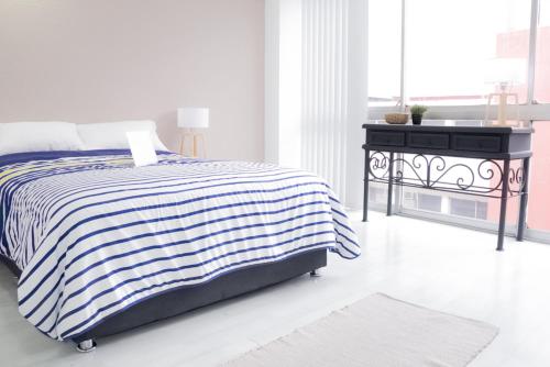 a white bedroom with a bed and a black table at Privada de Horacio 18 Residences in Mexico City