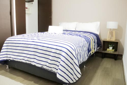 a bedroom with a bed with a blue and white striped blanket at Privada de Horacio 18 Residences in Mexico City