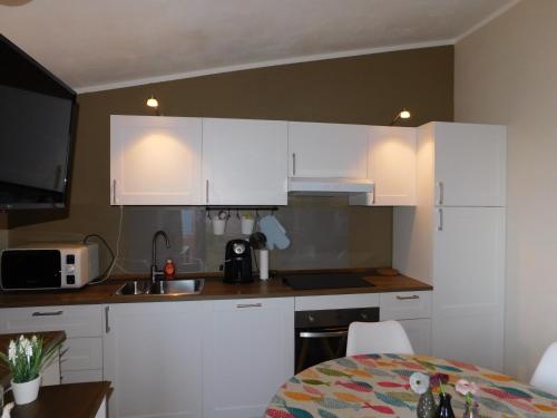 a small kitchen with white cabinets and a table at Il doppio nodo in Castelsardo