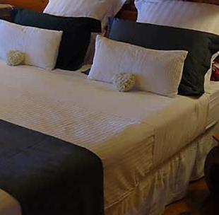 ein großes Bett mit weißen Kissen darauf in der Unterkunft Bunga-lodge VANILLE in Saint-André