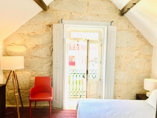 a bedroom with a red chair and a window at Romantic - Casa Rua Bela in Porto
