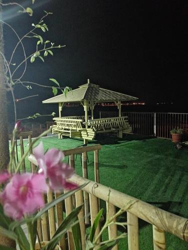 a wooden fence with a gazebo with pink flowers at Alshumukh guesthouse in Al Ghalīlah