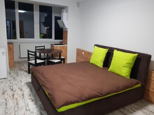 a bedroom with a bed with yellow pillows and a table at Silver Star Apartment 40b in Uzhhorod