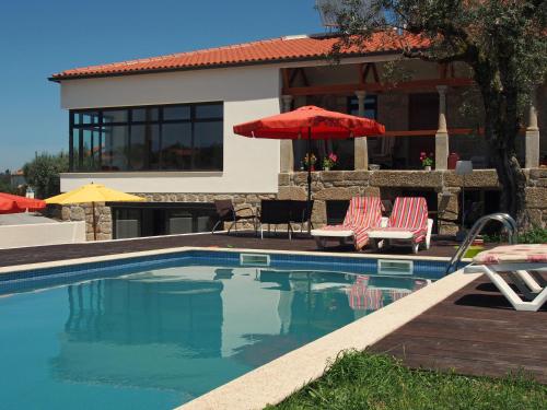 a swimming pool with two chairs and an umbrella at Casa Branca in Covas