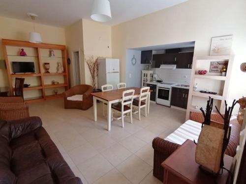 uma sala de estar com uma mesa e uma cozinha em Ktima Nafsika - Ground-floor luxury apartment in idyllic estate! em Porto Heli