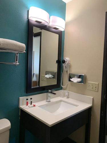 a bathroom with a sink with a mirror and a toilet at Super 8 by Wyndham Huron in Huron