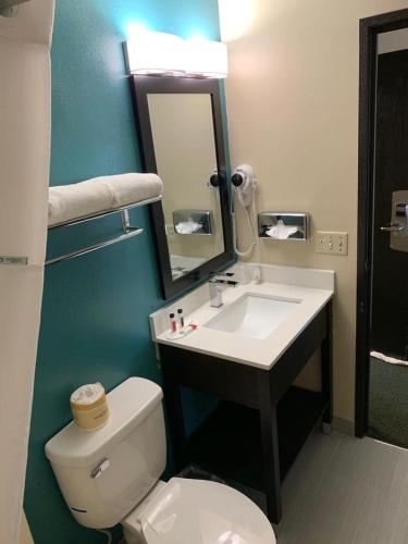 a bathroom with a toilet and a sink and a mirror at Super 8 by Wyndham Huron in Huron