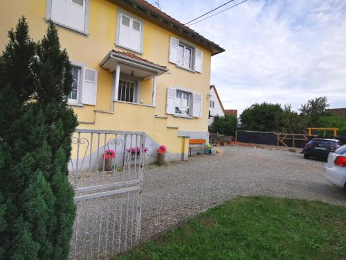 a yellow house with white windows and a fence at Au coeur de l'Alsace in Eschau