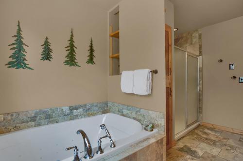 ein Badezimmer mit Badewanne und Dusche mit Bäumen an der Wand in der Unterkunft Pikes Peak Guest Cabin at Rocky Mountain Lodge in Cascade-Chipita Park