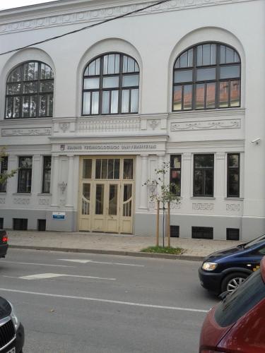 a white building with windows and doors on a street at Jolando Apartment in Kaunas