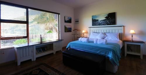 a bedroom with a bed with blue sheets and two windows at Anglers Paradise in Eersterivierstrand