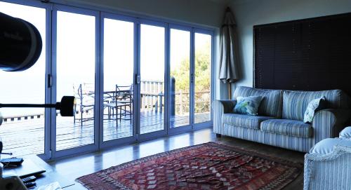 a living room with a couch and a sliding glass door at Anglers Paradise in Eersterivierstrand