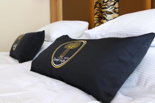 two black pillows on a bed with a black and gold pillow at Baobab Suites in Siófok