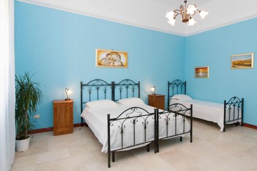 a blue bedroom with two beds in it at Li Cuti B&B in Tiggiano