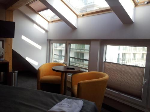 ミエンジズドロイェにあるWilla Plażowaの椅子2脚、テーブル、窓が備わる客室です。