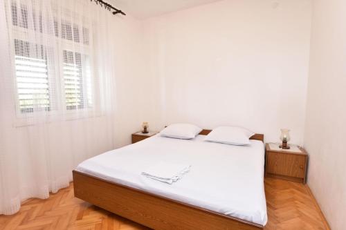 een witte slaapkamer met een bed en een raam bij Apartment Damir in Primošten