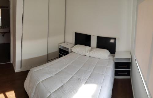 1 dormitorio con 1 cama blanca y 2 mesitas de noche en Tu lugar en Villa en Villa Constitución