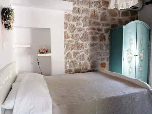 ein Schlafzimmer mit einem Bett und einer Steinmauer in der Unterkunft Ktima Nafsika - First-floor luxury apartment in majestic estate in Rozaíika