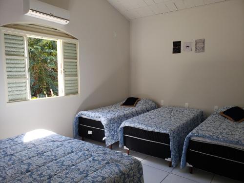 three beds in a room with a window at Rancho Garcinha - Lago de Furnas in São José da Barra