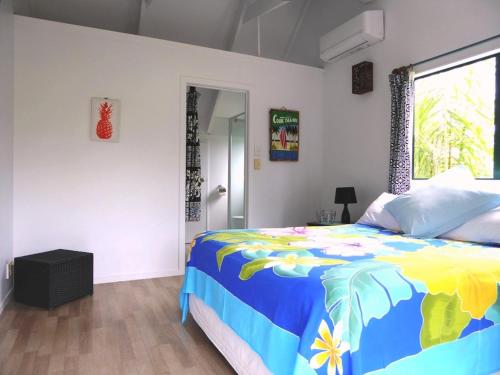 a bedroom with a colorful bed and a window at Taakoka Muri Beach Villa in Rarotonga