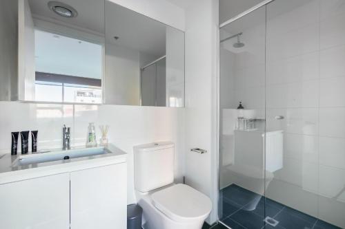 a white bathroom with a toilet and a shower at Lux 2BR Apt on Hindmarsh SQ-Pool-Gym-Sauna-Parking in Adelaide