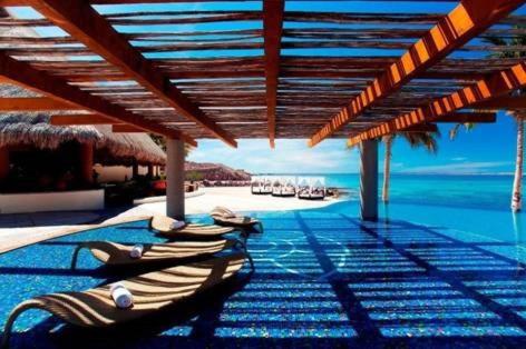 a pool with chaise lounges and the ocean at Casa Tu Paz in La Paz