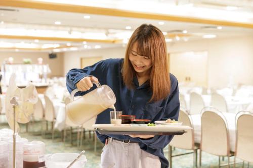 a woman is holding a plate of food at Aishinkan in Morioka